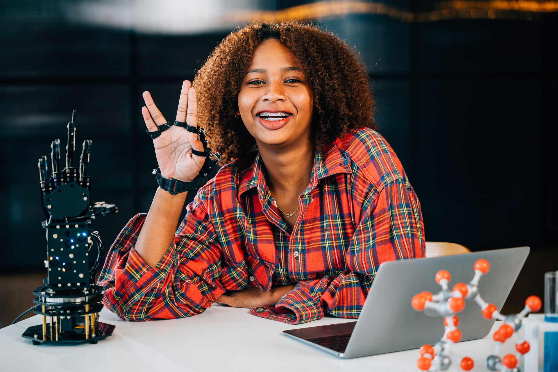 Black teenage student in a classroom learns and tests a robotic arm discovering subjects of interest. Embracing innovation and technology for skill development in joyful education.