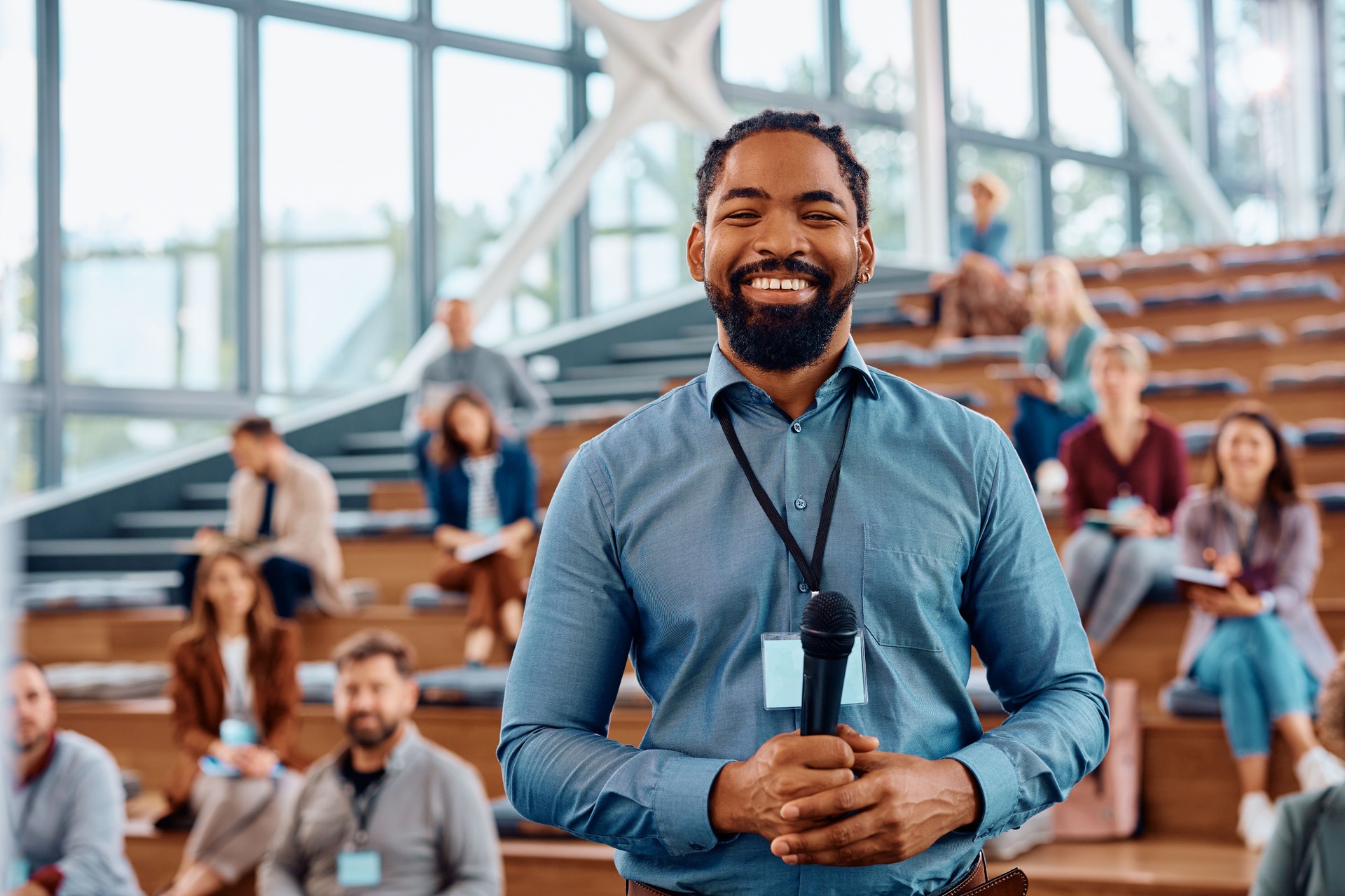 Happy black public speaker during business conference in convention center looking at camera.